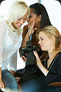 Three women watching at SLR camera.
